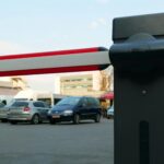 Close-up of a parking lot barrier gate with vehicles in the background, modern and automated.