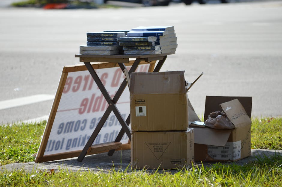 Outdoor display of books and cardboard boxes on a stand, perfect for yard sale or flea market.